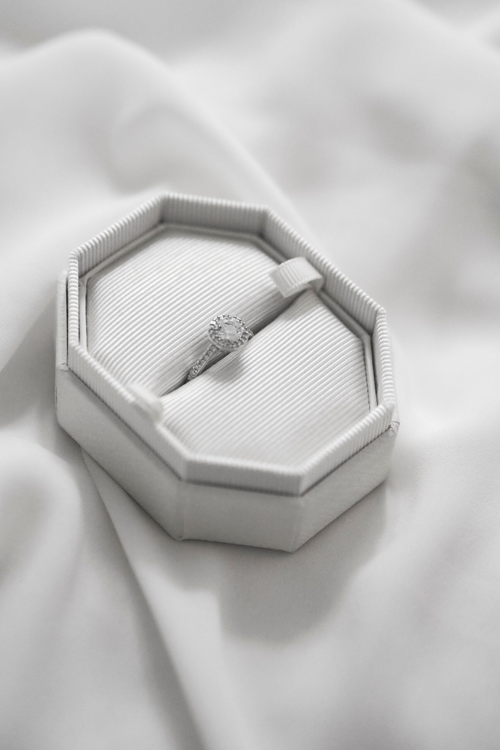 Solitaire verlovingsring met diamant in een witte achthoekige ringdoos op zijdeachtige stof